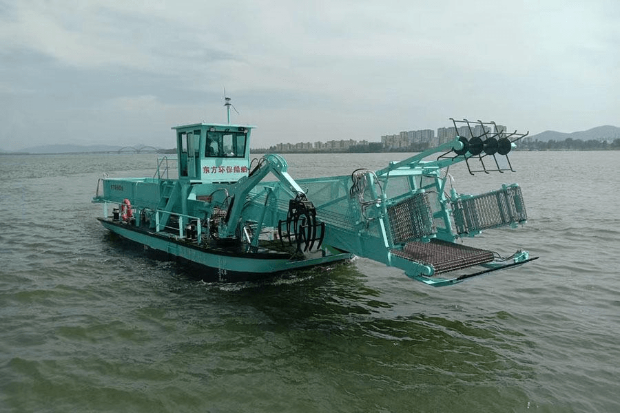 Fully automatic water surface cleaning vessel with a grab arm